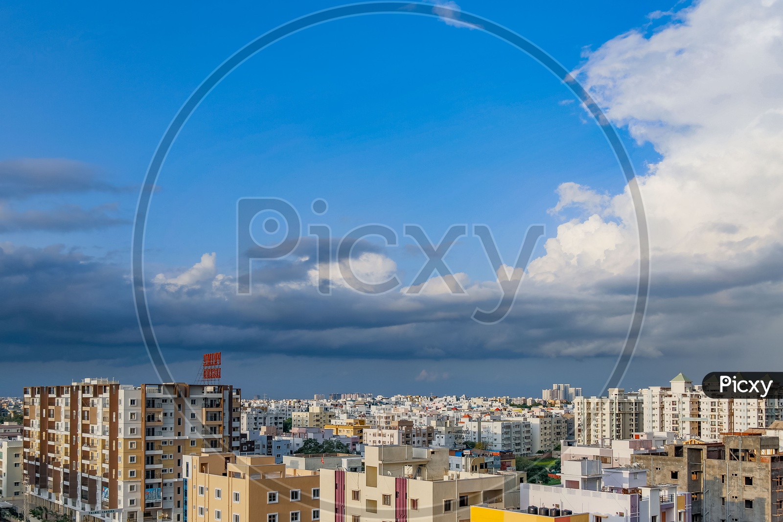 City Scape View With Apartments And Cotton Clouds In Blue Sky