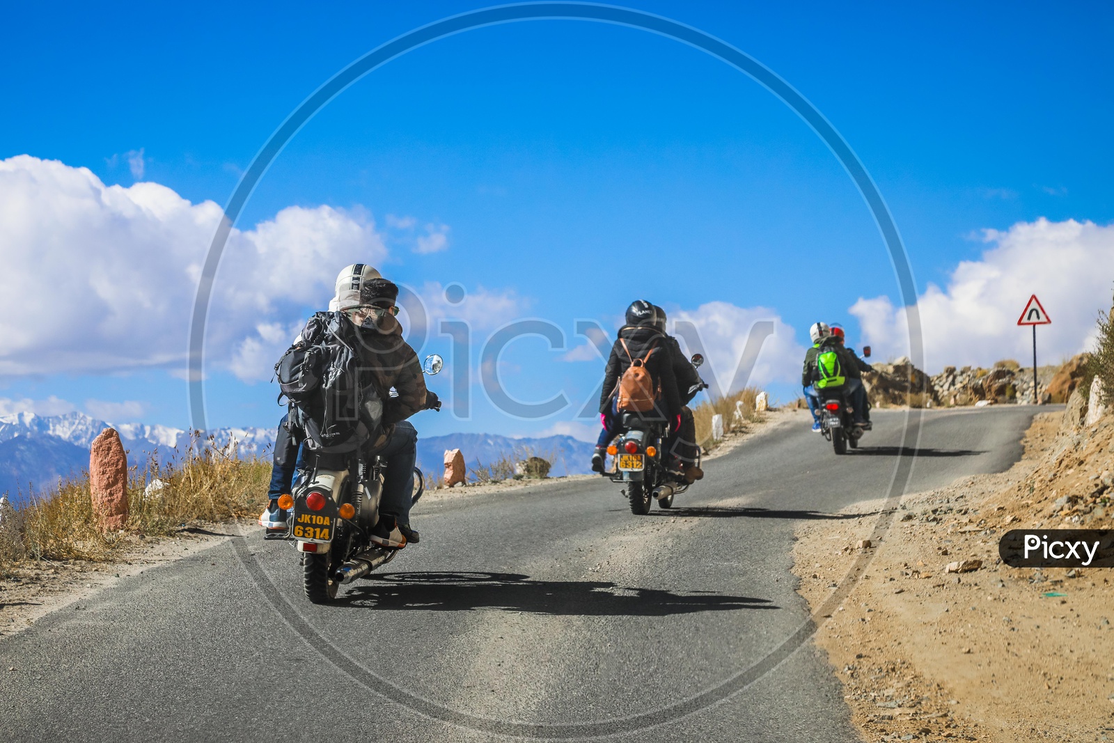 Travellers on three motorcycles by the roadway through the hills