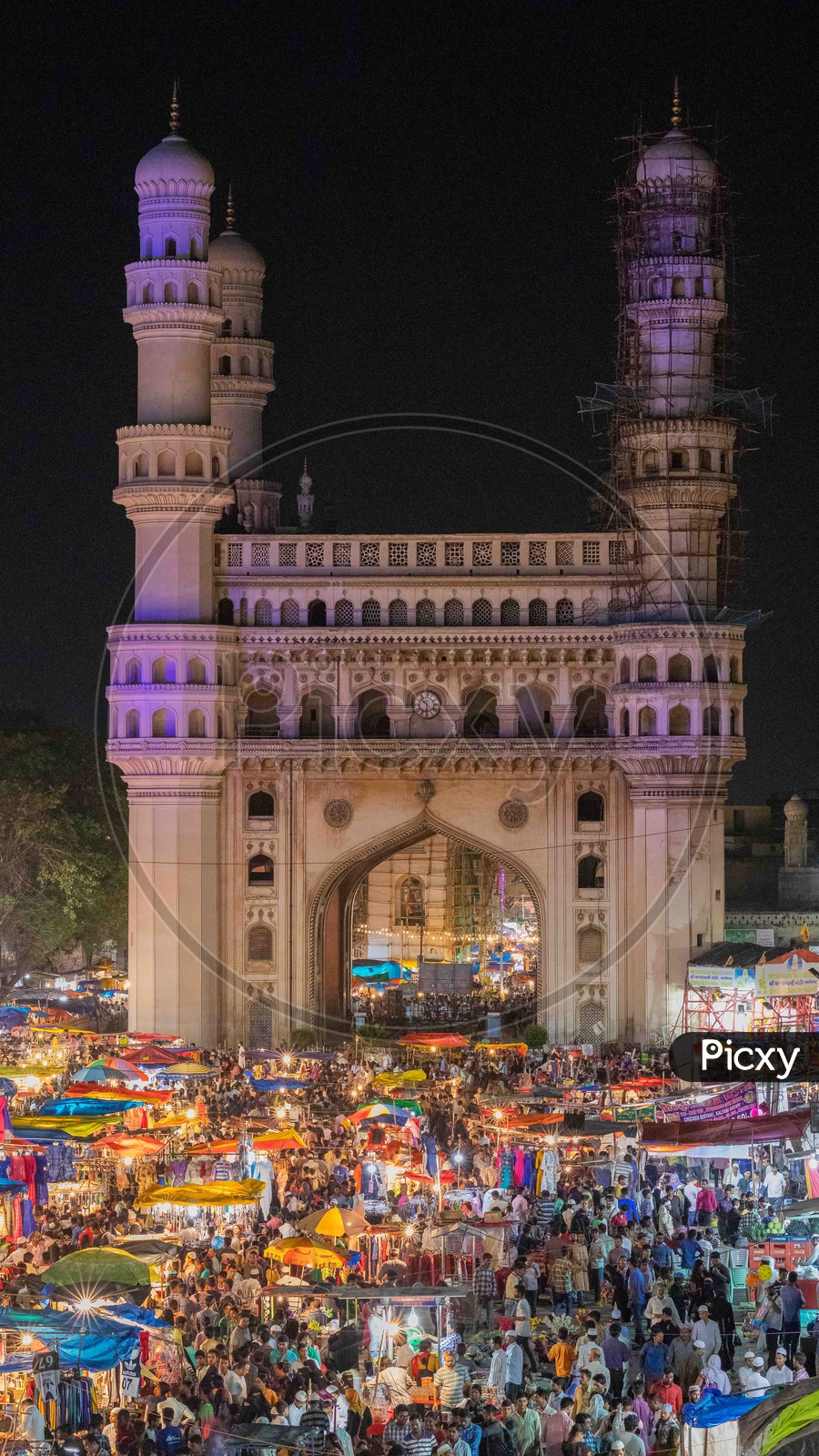Crowd in street bazaar during night with Charminar in background