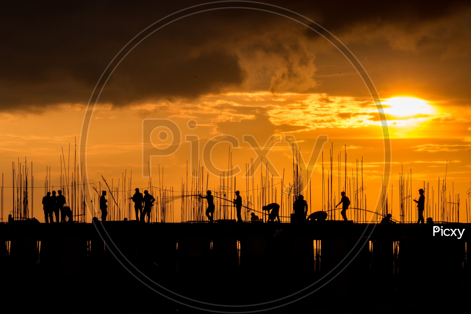Silhouettes of A Construction Site With Workers On the Roof Top And with Golden Yellow Sky in Background