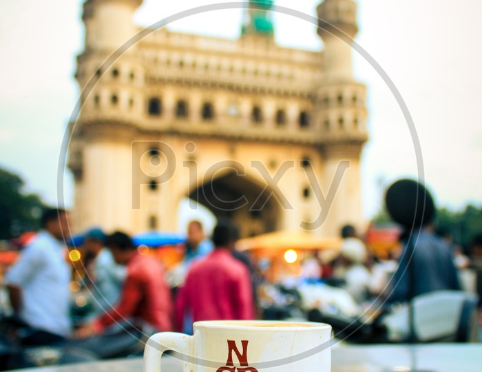 Tea cup and a saucer on the table with Charminar in background