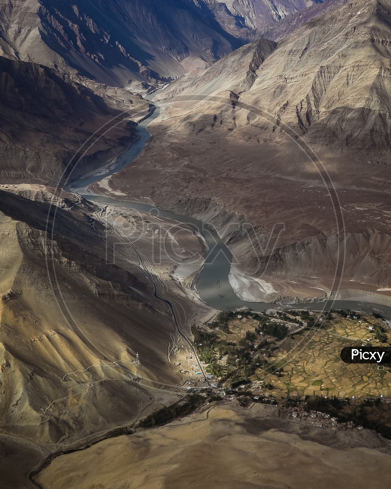 Aerial view of the Indus River flowing through the mountains alongside the crops