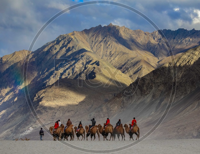 Landscape of travellers experiencing camel ride along with the rainbow over the mountains