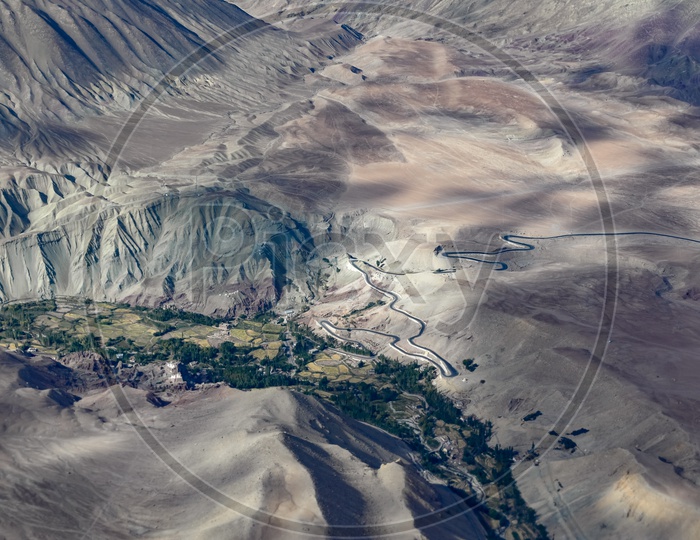 Aerial view of the Indus River alongside the crops with sandstone mountains