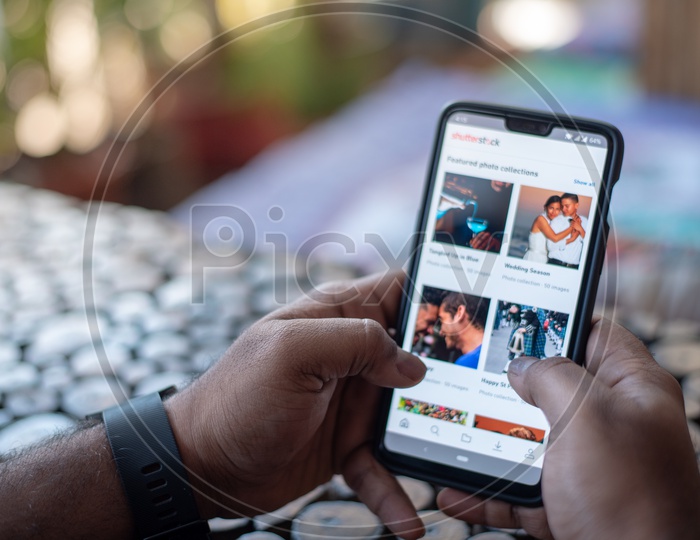 Indian Man using Shutterstock App in Smart Phone