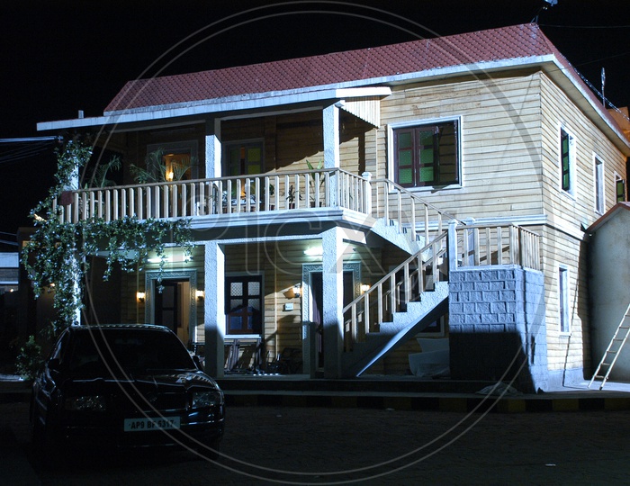 Wooden house in the night with a black car parked in front of it