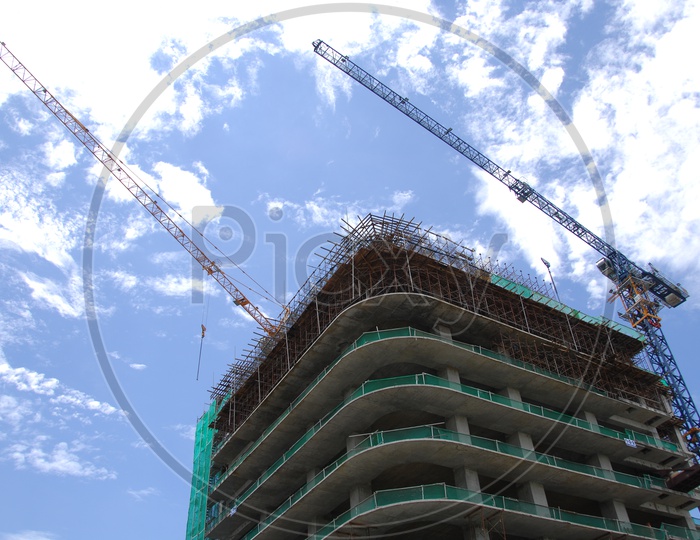 Tower Cranes alongside the High Rise Buildings with cloudy blue sky in background
