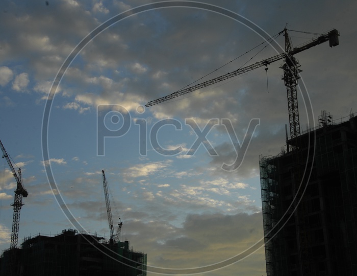 Tower cranes alongside the construction of hi rise buildings with cloudy sky
