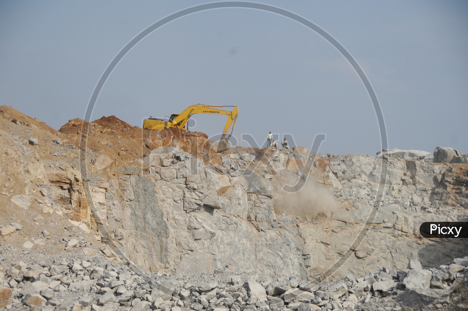 Bulldozer quarrying the construction area of rocky hill alongside the workers