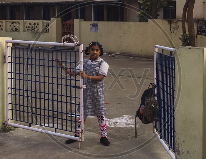 Little girl standing by the gate to go to school