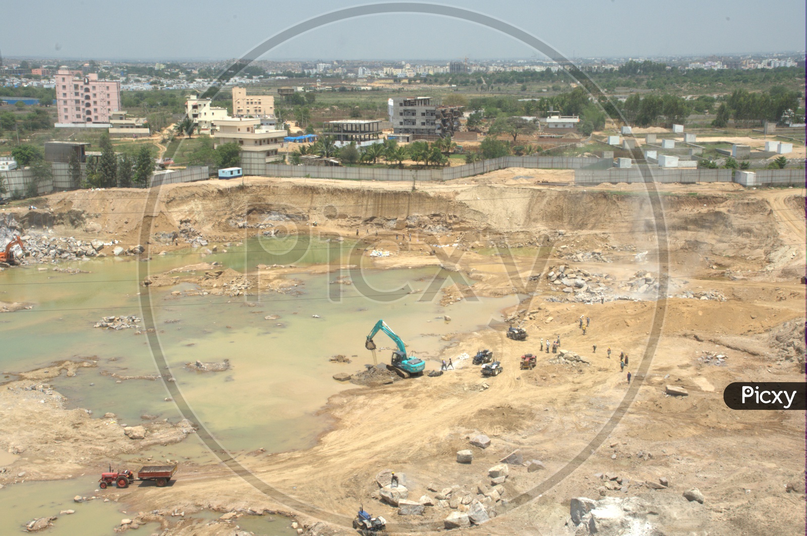 Aerial view of Bulldozer excavating the rock bodies alongside the labourers drilling at a construction site