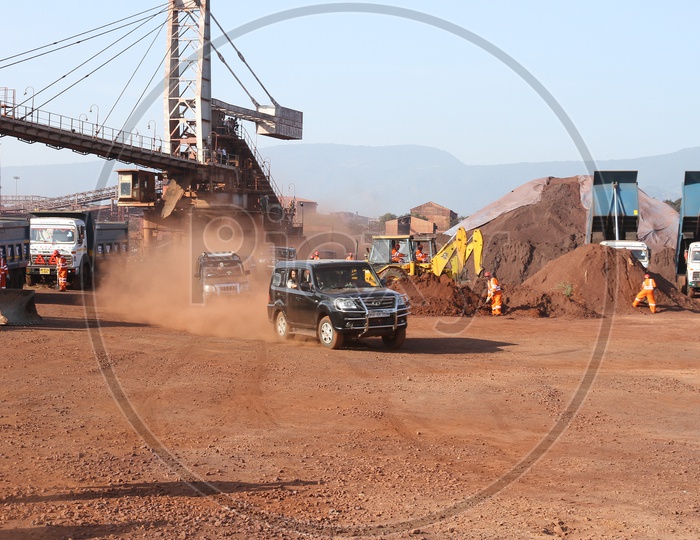 Moving cars alongside the workers wearing safety dress working at a construction site