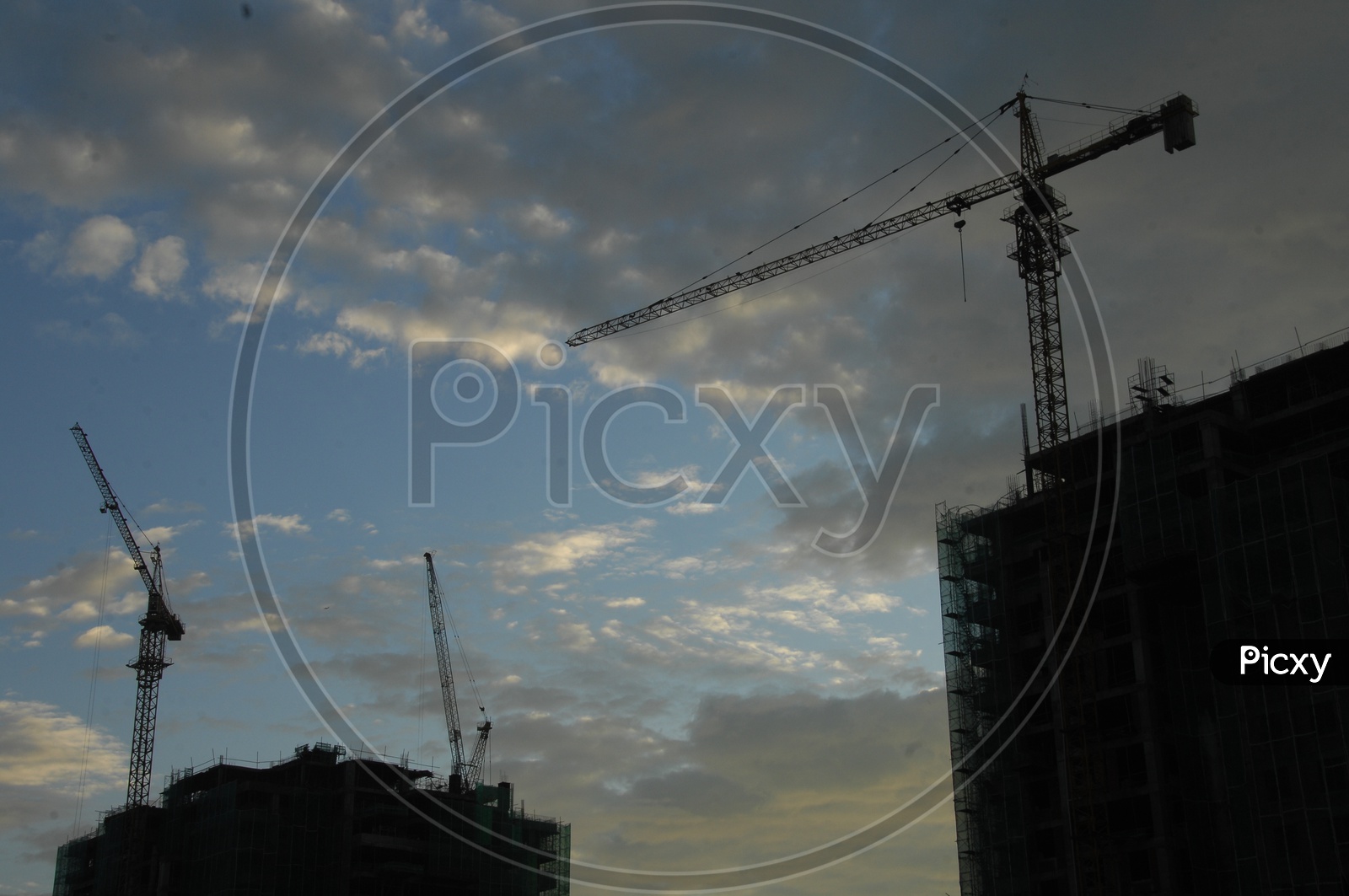 Tower cranes alongside the construction of hi rise buildings with cloudy sky