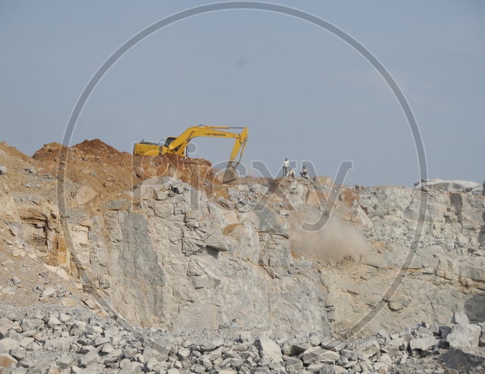 Bulldozer quarrying the construction area of rocky hill alongside the workers