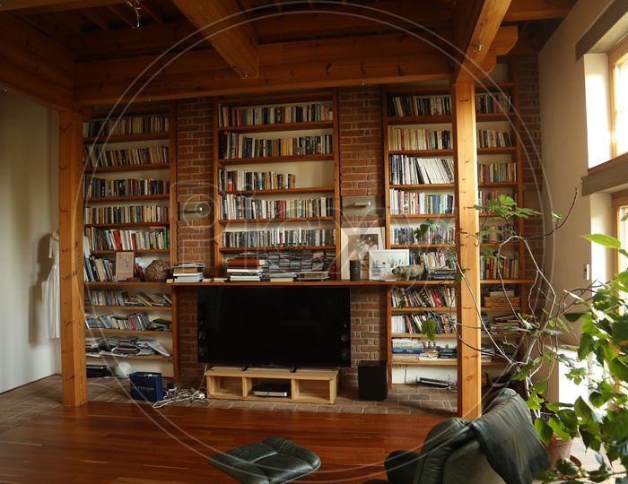 Book shelves in a room with led TV, a chair and an indoor plant