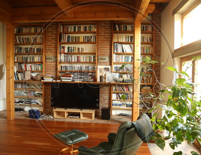 Book shelves in a room with led TV and a chair