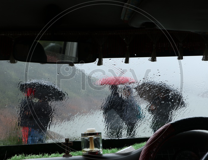 Tourists under Umbrellas on a rainy day watching a water channel from hill top