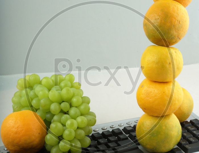 Photograph of Orange and grapes placed on computer keyboard