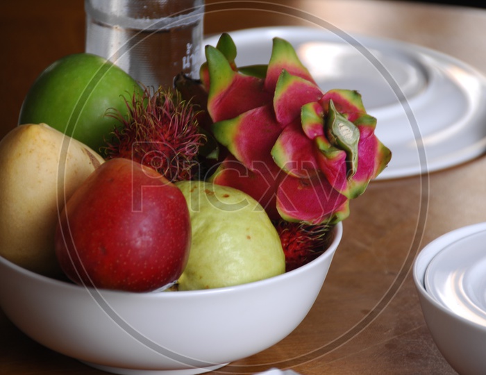 Close up shot of fruits in a white bowl on a dining table