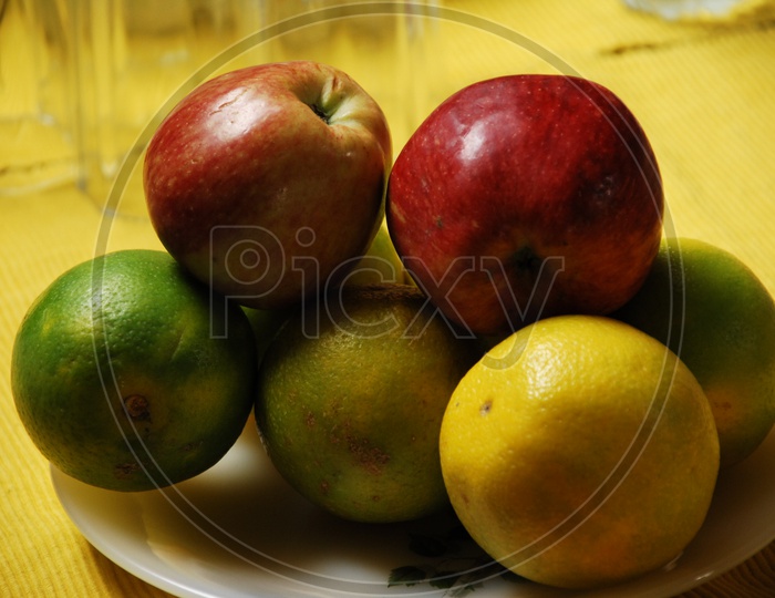 Photograph of fruits in a plate with yellow background
