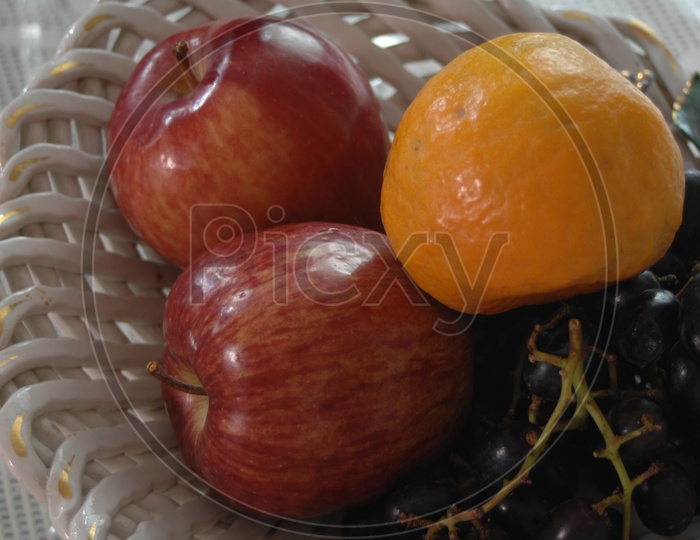 Photograph of apples and orange fruits in a bowl
