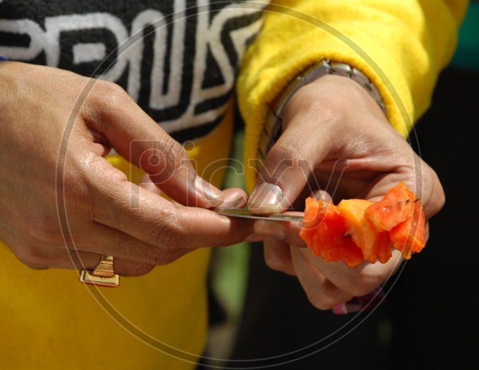 Man holding papaya fruit pieces with a fork