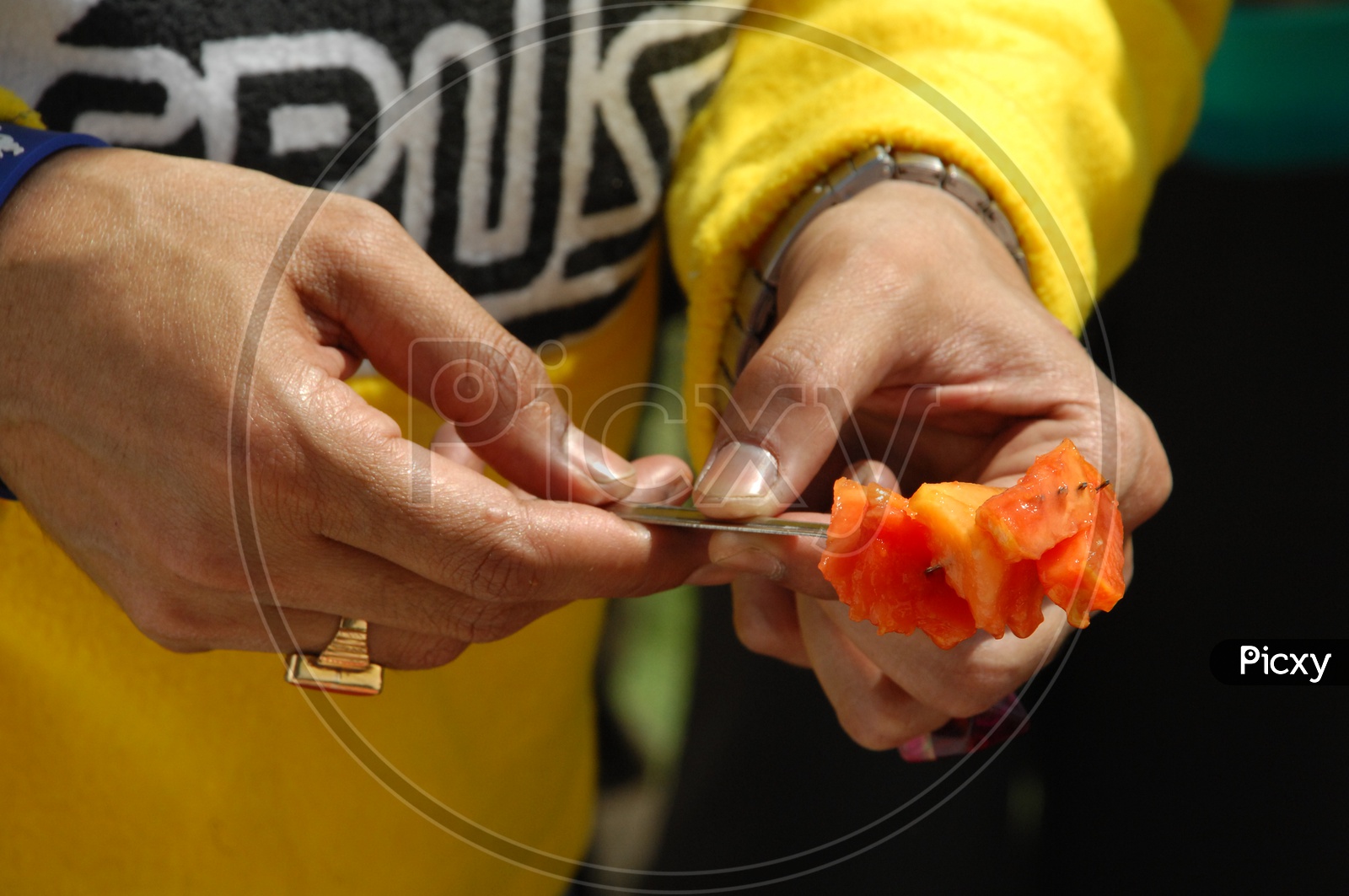 Man holding papaya fruit pieces with a fork