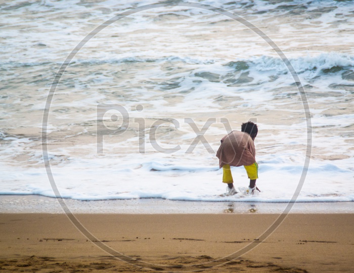 Boy taking water from beach in a bottle