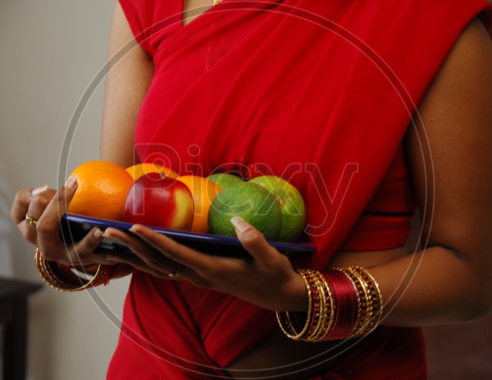 A women holding a plate of fruits in hands