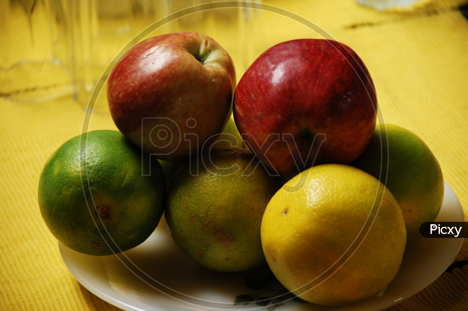 Photograph of fruits in a plate with yellow background