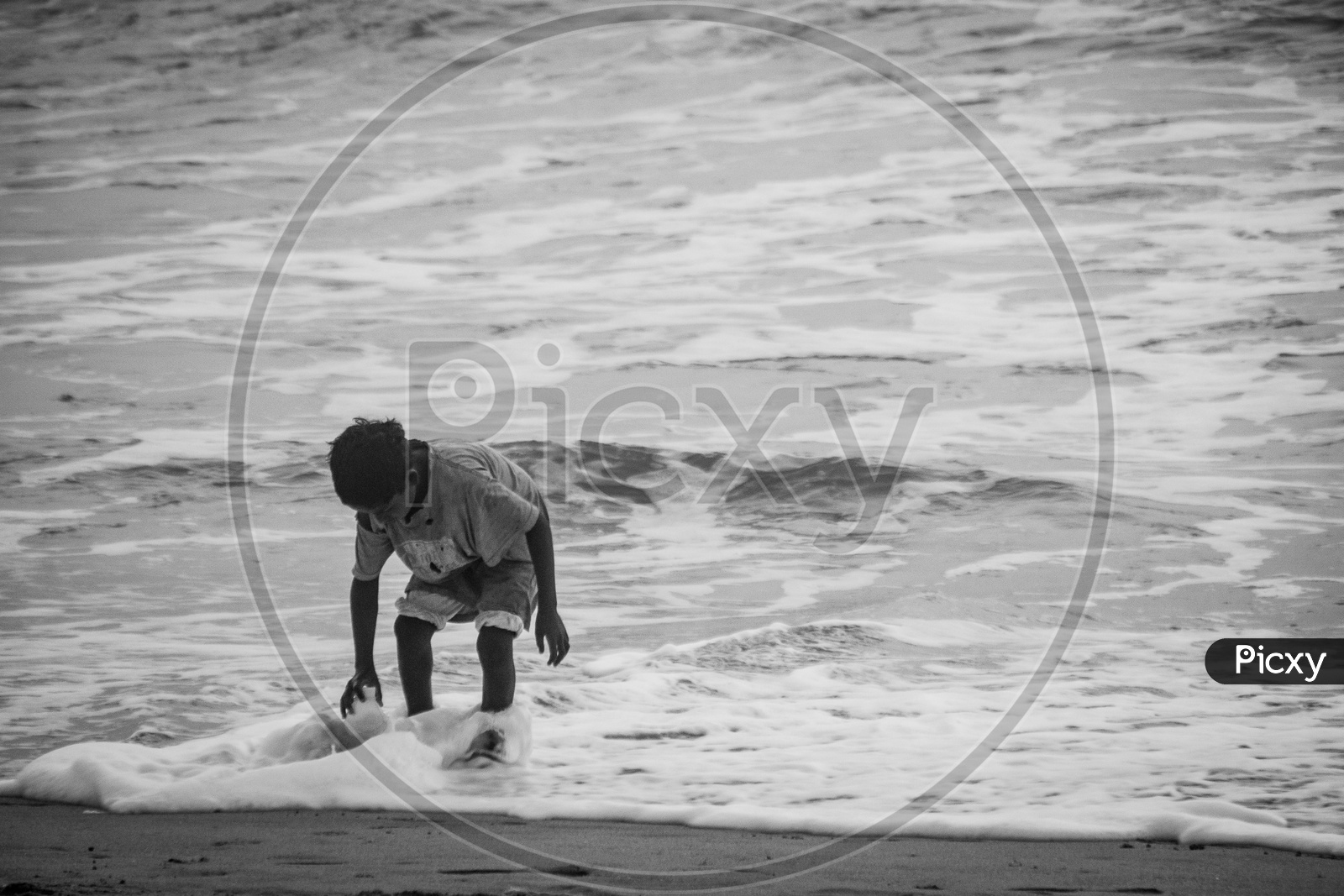 Boy taking water from beach in a bottle