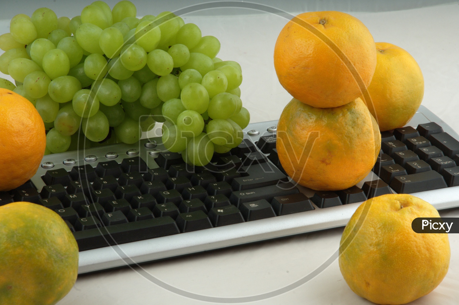 Photographs of oranges and grapes on a computer keyboard