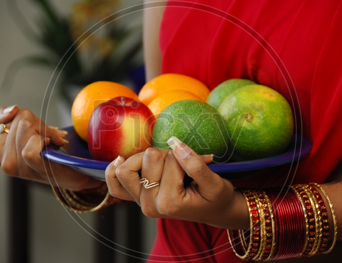 A women holding a plate of fruits in hands
