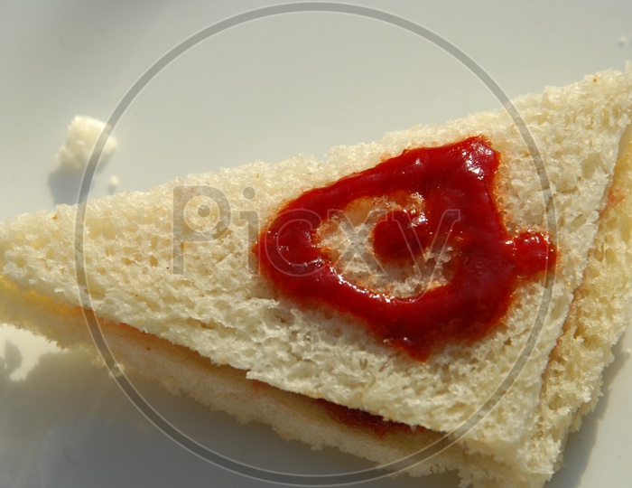 Bread sandwich with tomato ketchup on top in a white plate