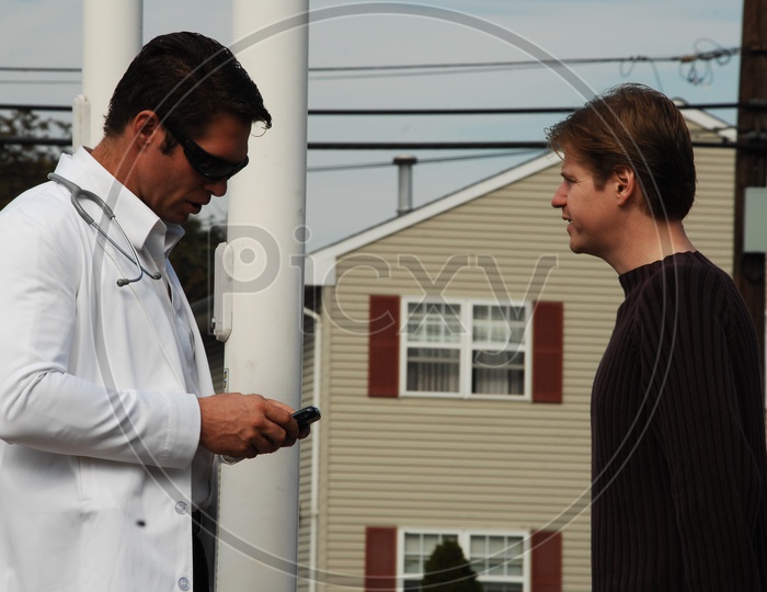 A male doctor with a white coat and stethoscope talking to a patient