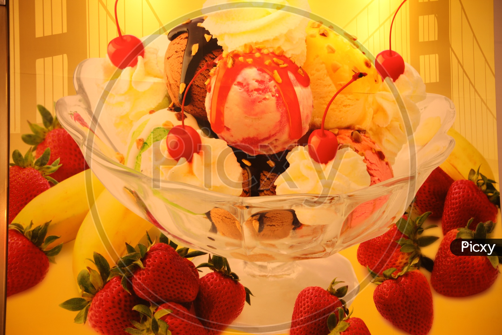 Ice cream scoops in a glass bowl topped with cherries and strawberries in the foreground