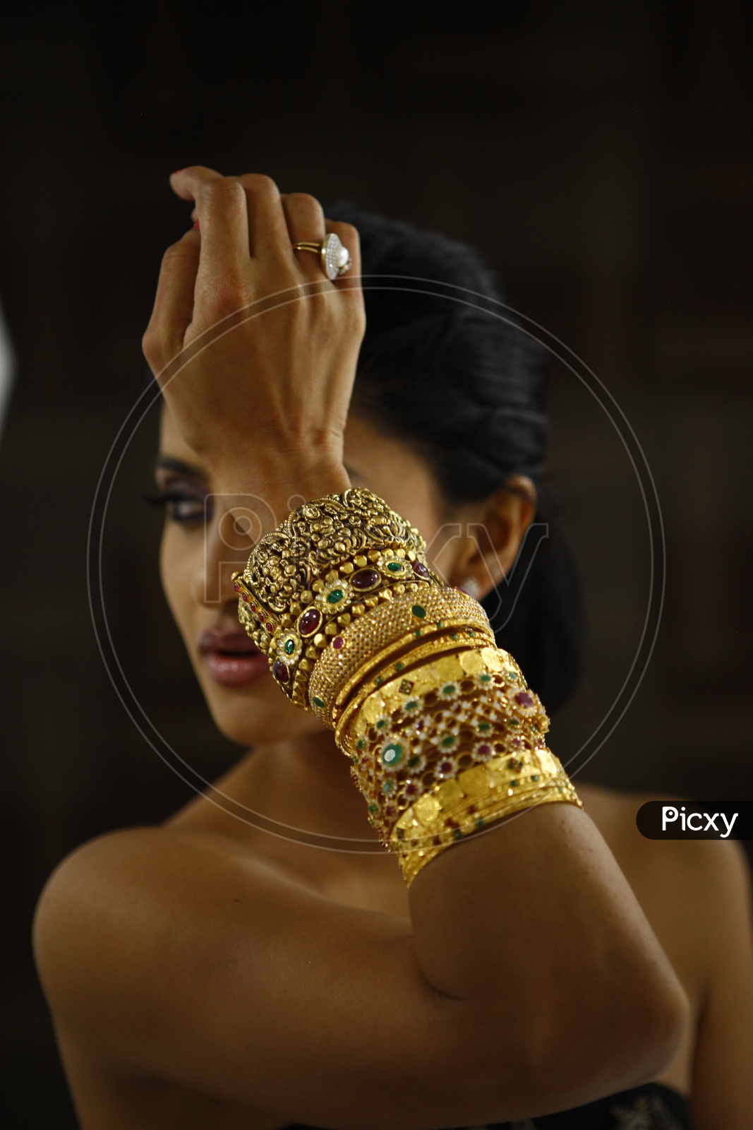 Female model wearing different types of gold bangles and a pearl finger ring