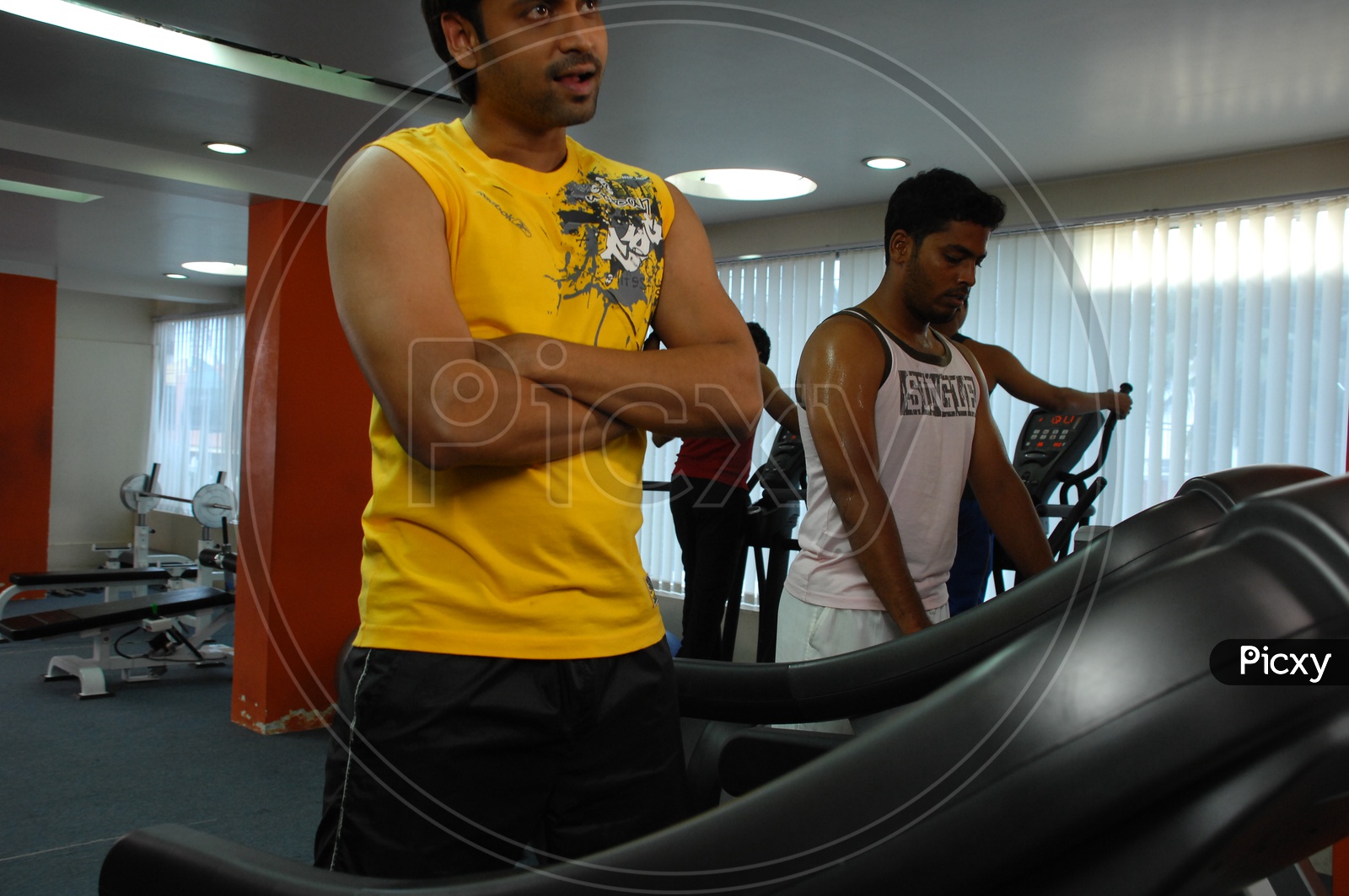 Actor Sumanth holding his hands with his mouth open alongside the treadmill in a Gym