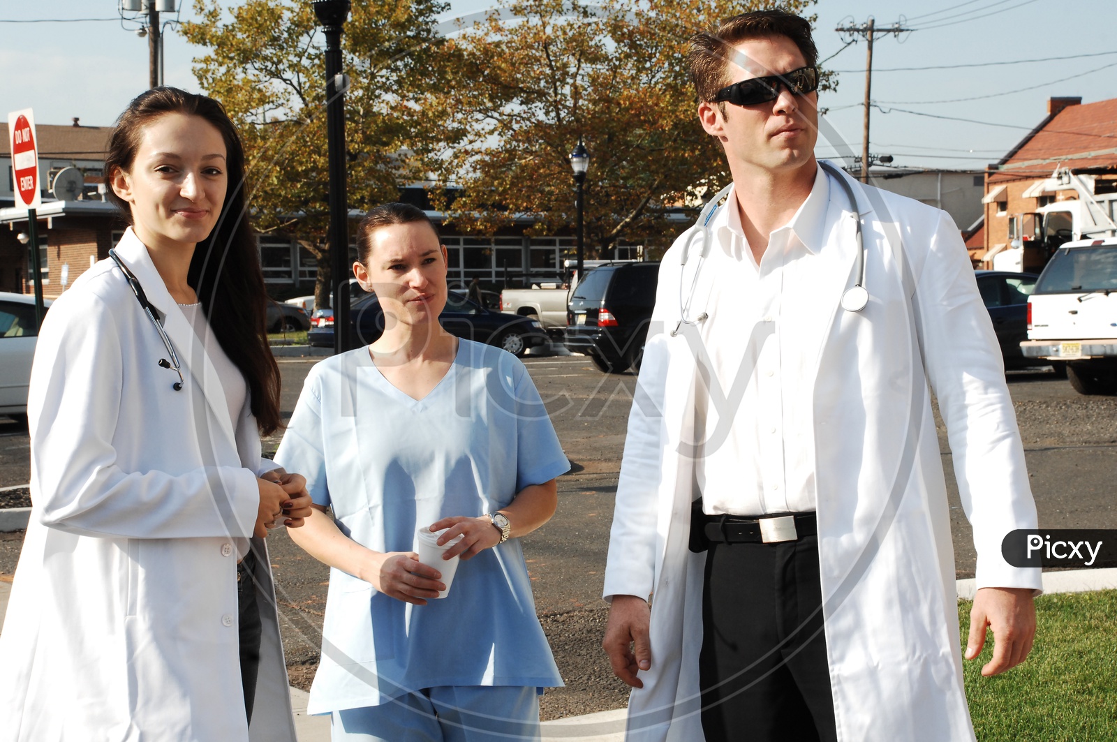 A male and a female doctors wearing white coat with stethoscopes and a patient on the road