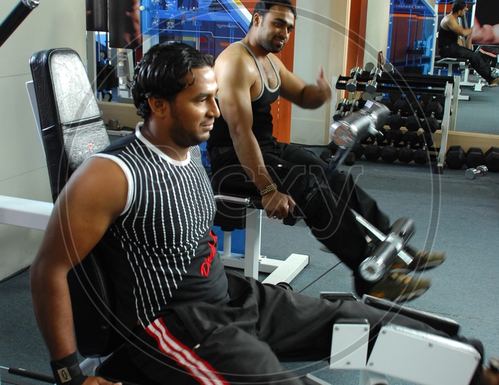 Two men doing leg exercises by the different leg machinery in a Gym