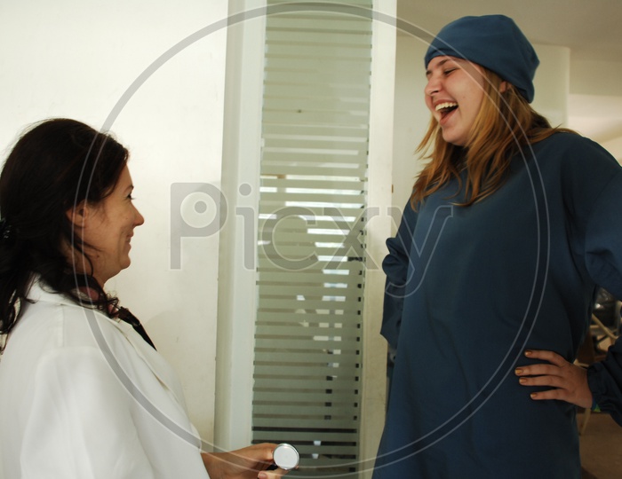 A female doctor with a white coat and stethoscope talking to patients