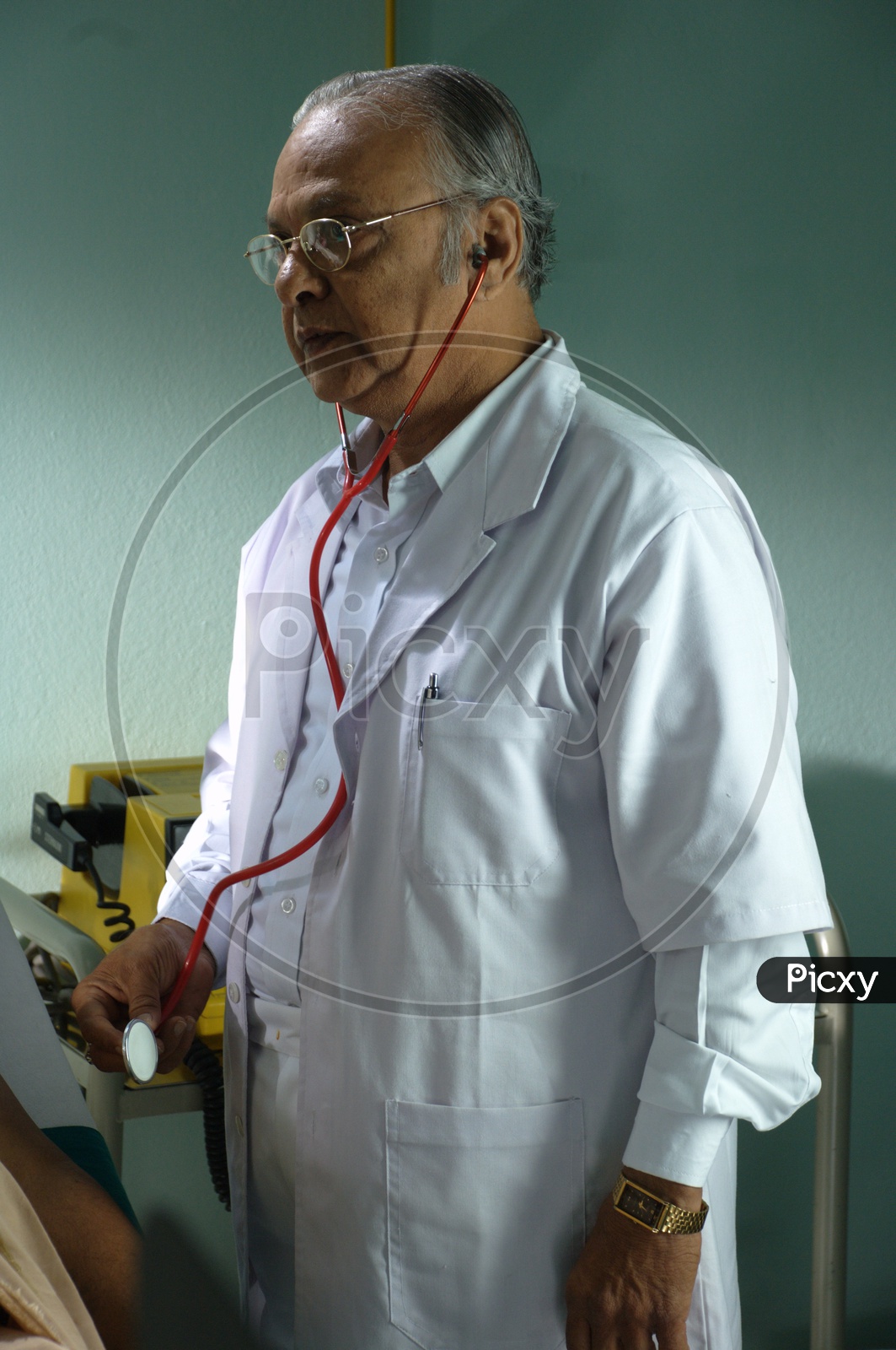 An old male doctor with stethoscope wearing a white coat