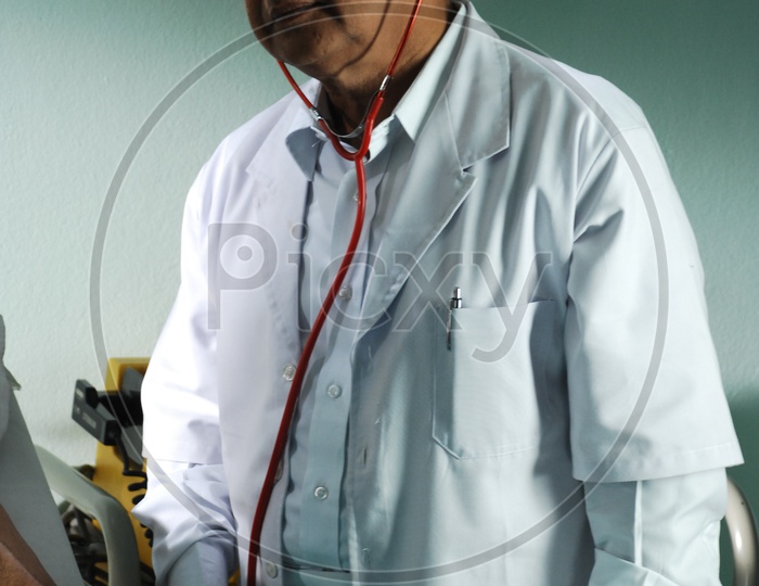 An old male doctor with stethoscope wearing a white coat