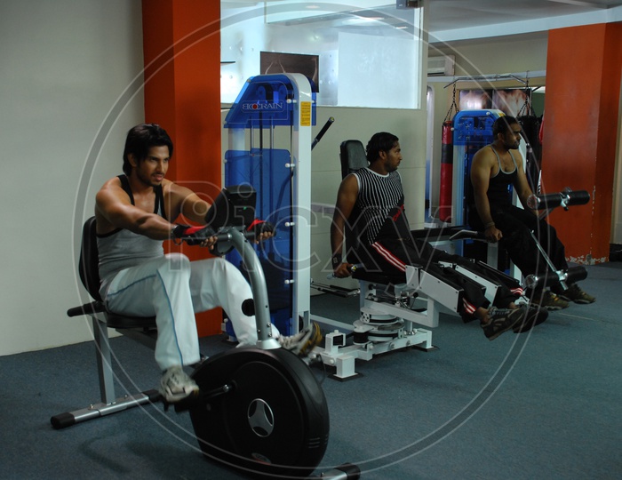 Indian men doing upright bike exercise in a Gym