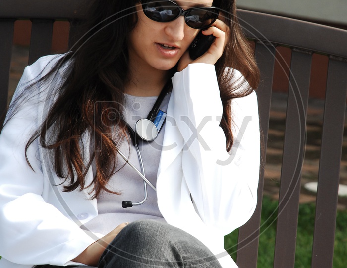 A female doctor wearing white coat with stethoscope talking over the mobile
