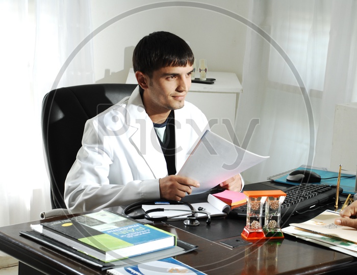 A male doctor with a stethoscope wearing a white coat sitting in the hospital cabin