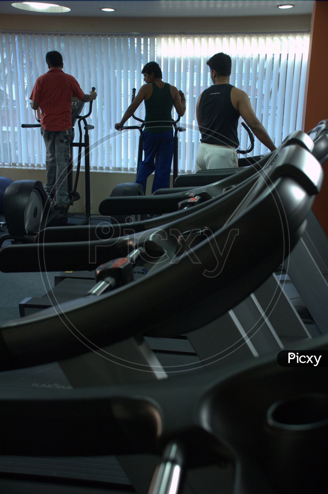 Group of men doing exercises alongside the treadmill in a Gym