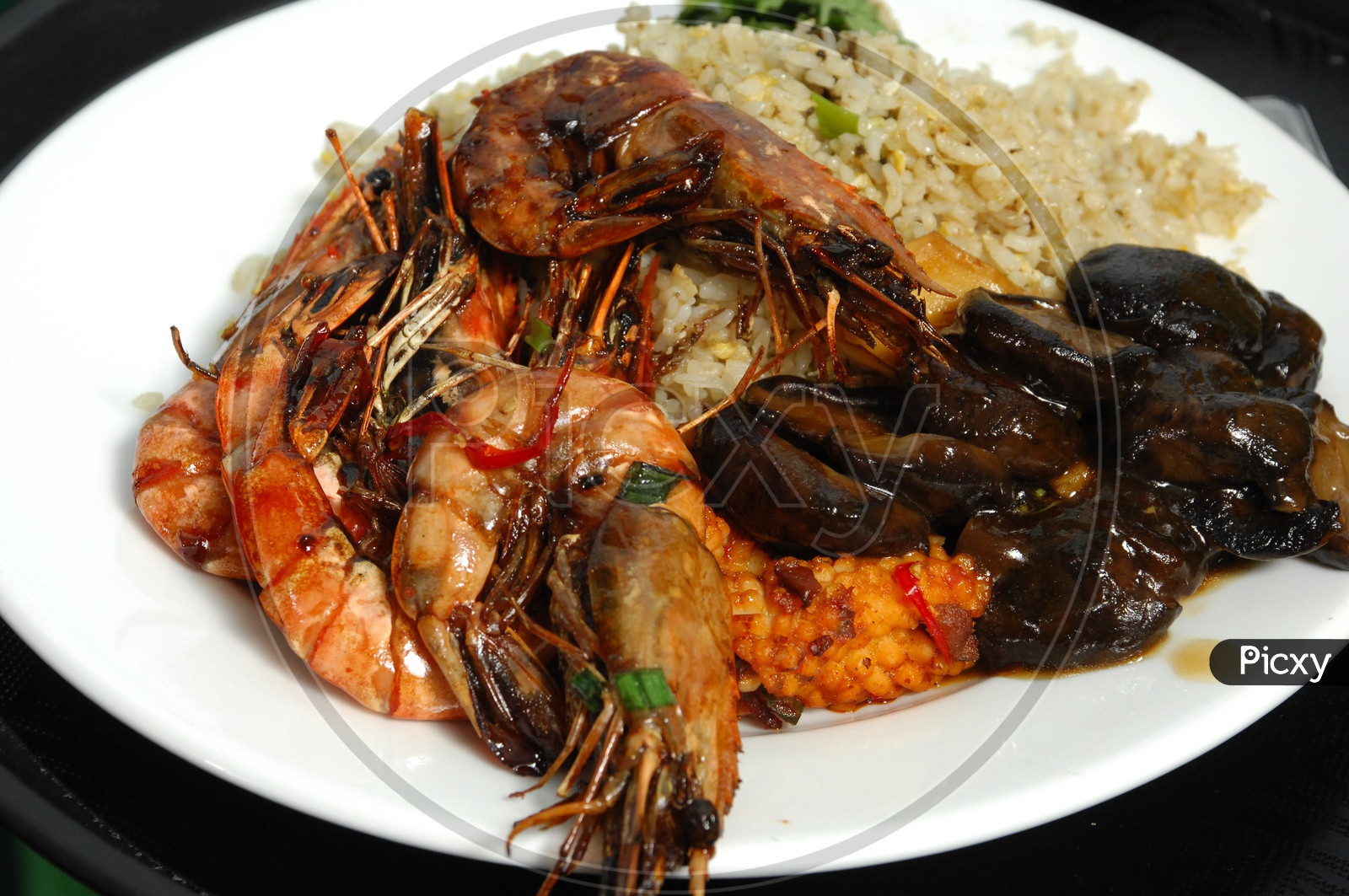 Cooked shrimp along with fried rice served in a white plate