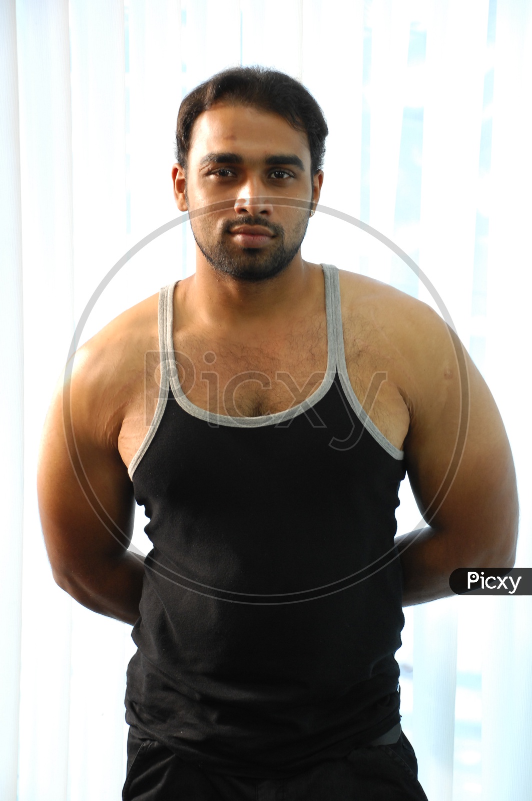 Image of A muscled man wearing black vest with his hand held backwards