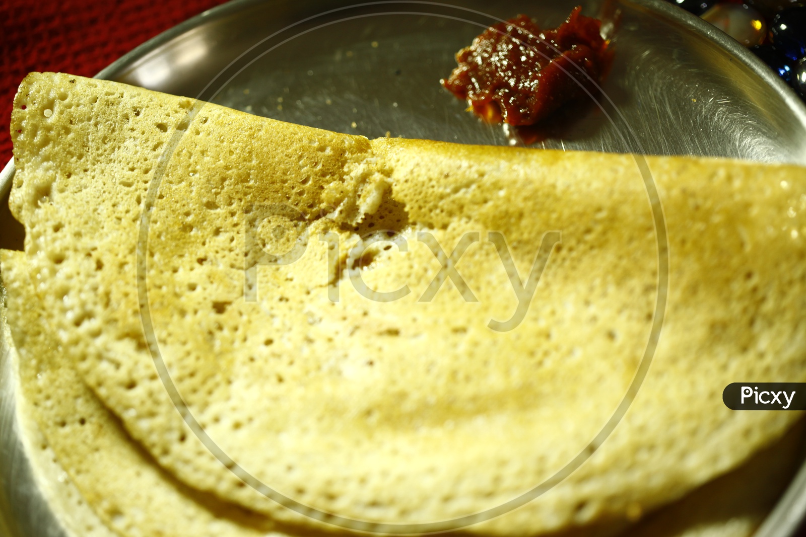 Dosa with a pickle served in a steel plate